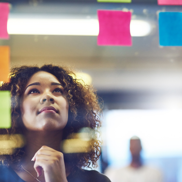 persoon die denkend kijkt naar bord met post its